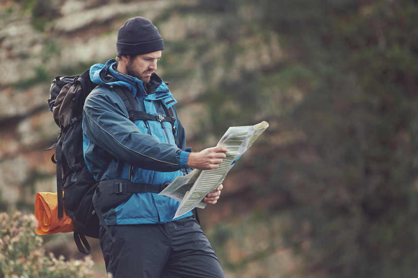 Man with map exploring wilderness on trekking adventure